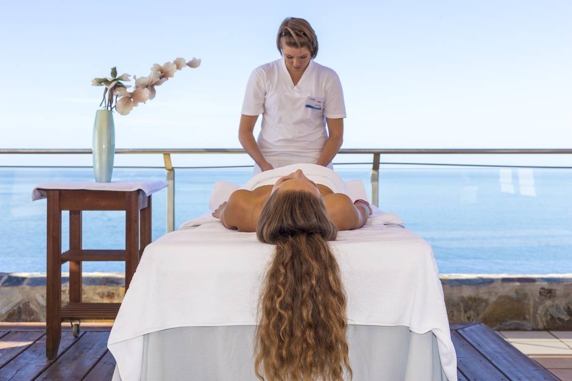 Eine Frau erhält eine Massage-Behandlung im Gloria Palace Amadores Thalasso & Hotel mit Blick auf das Meer.