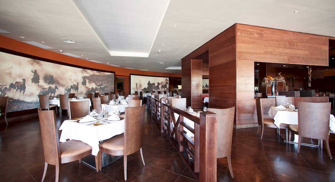 Innenansicht des Restaurants im Barcelo Bavaro Palace Hotel mit gedeckten Tischen und Holzelementen.