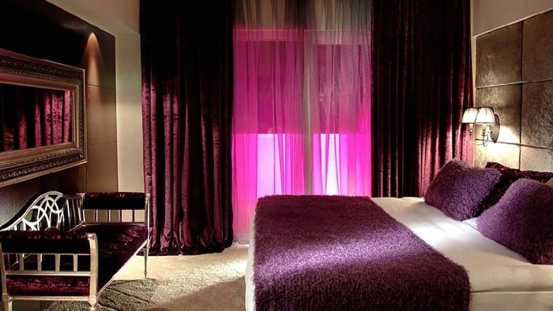 Schlafzimmer im Sealife Buket Resort & Spa mit violetten Vorhängen und pinkem Licht.