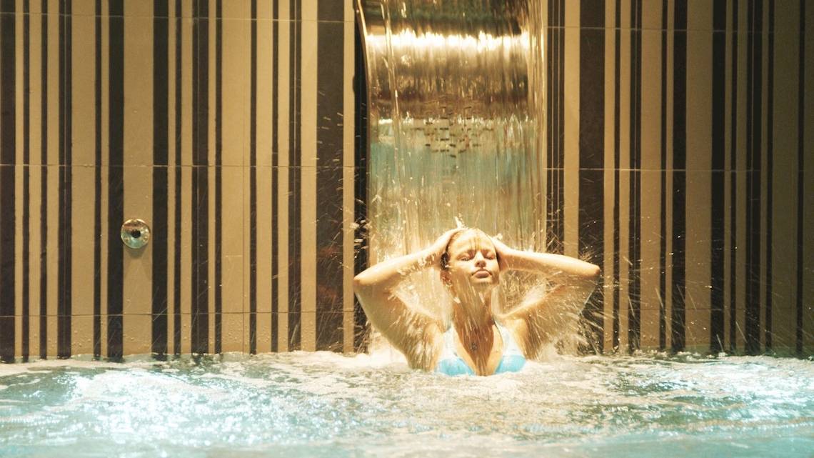 Frau im HD Beach Resort Pool unter einem Wasserfall