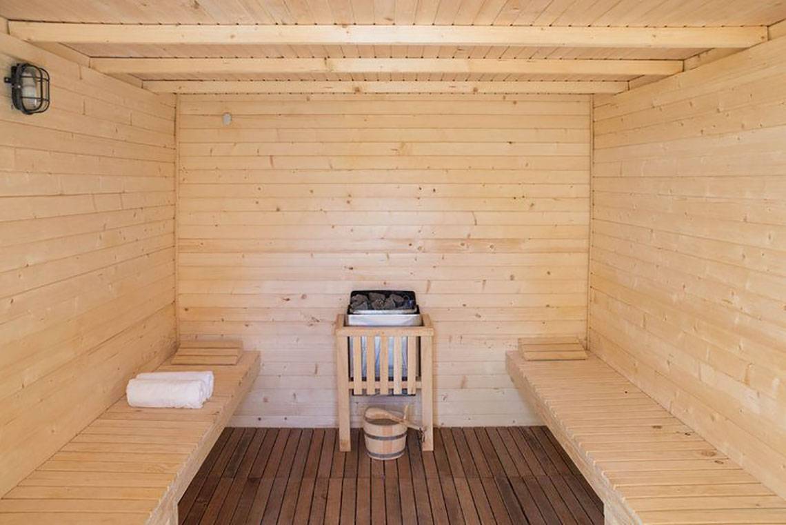 Innenansicht der Sauna im Gran Canaria Princess Hotel mit Holzbänken, einem Holzofen und Handtüchern.