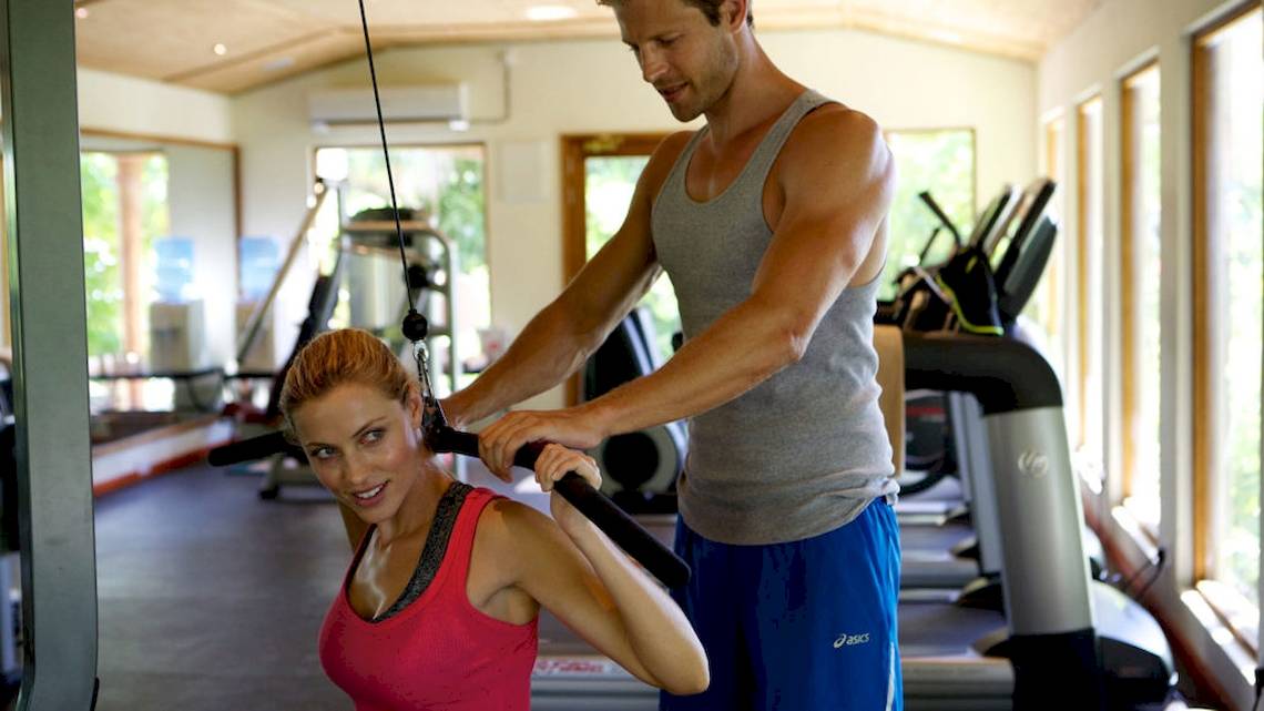 Ein Fitnesstrainer hilft einer Frau im Gym, Übungen durchzuführen.