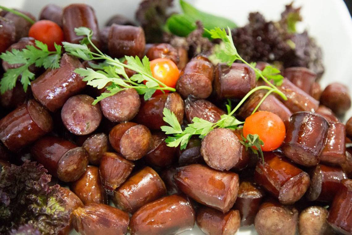 Nahaufnahme von gegrillten Würstchen mit Tomaten und Petersilie