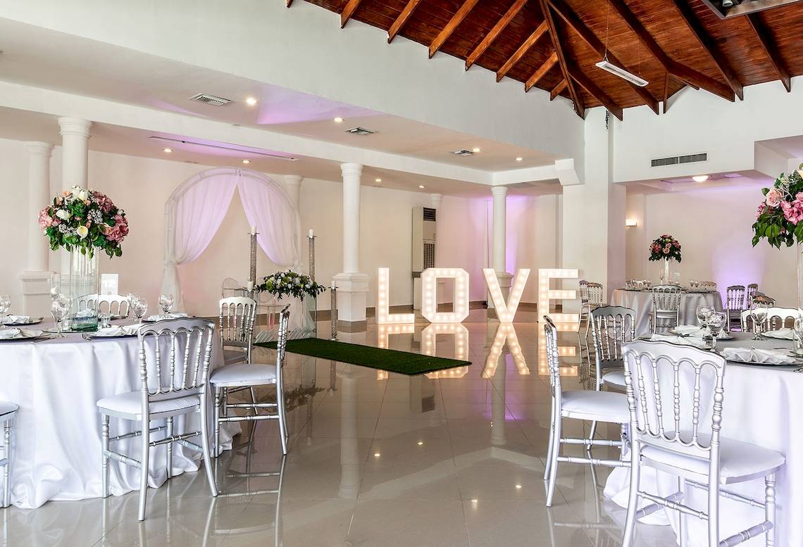 Hochzeitssaal im Sunscape Coco Punta Cana mit großen LOVE-Buchstaben und gedeckten Tischen.