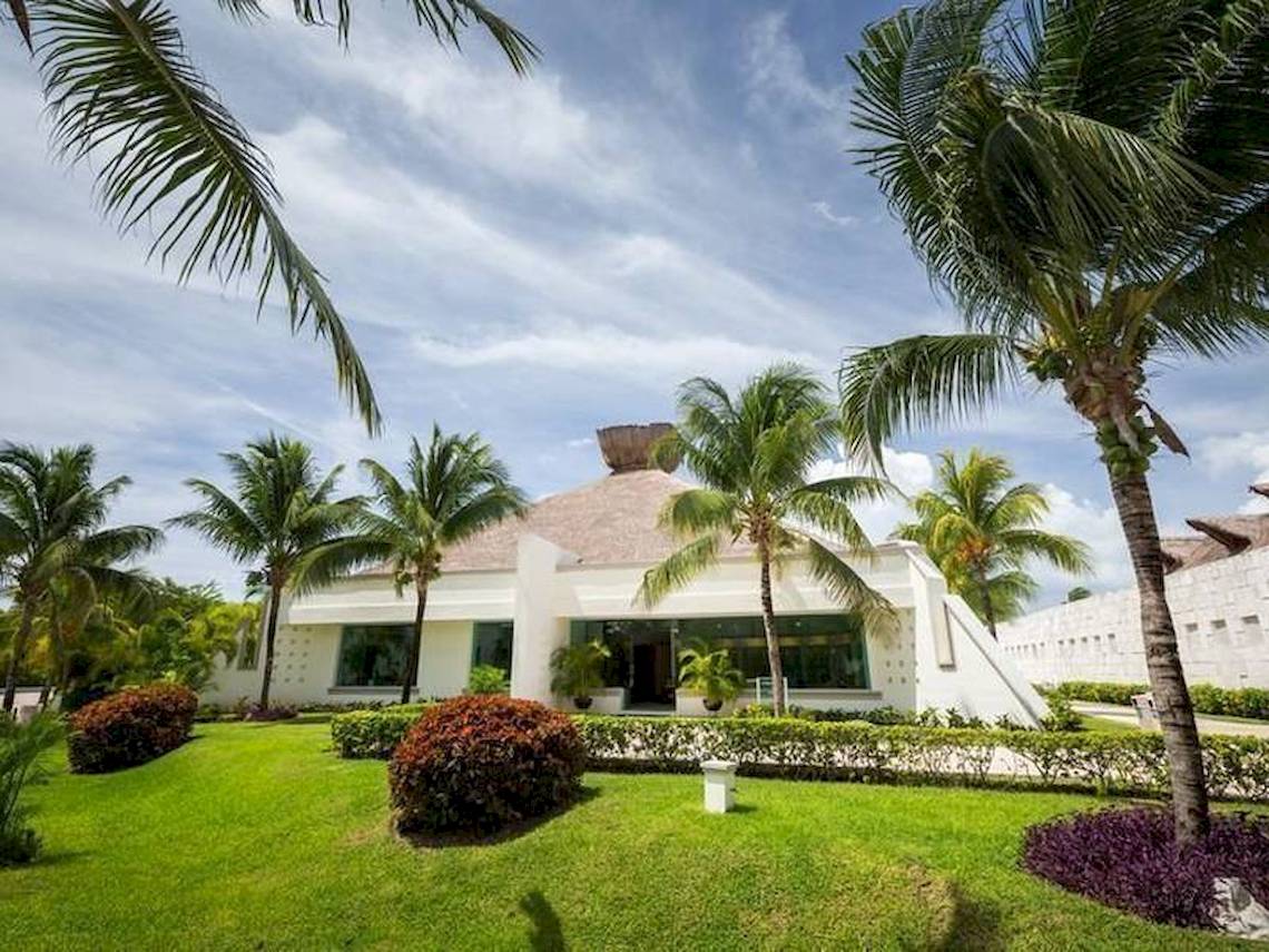 Außenansicht des BlueBay Grand Esmeralda Hotels mit gepflegtem Rasen und Palmen.