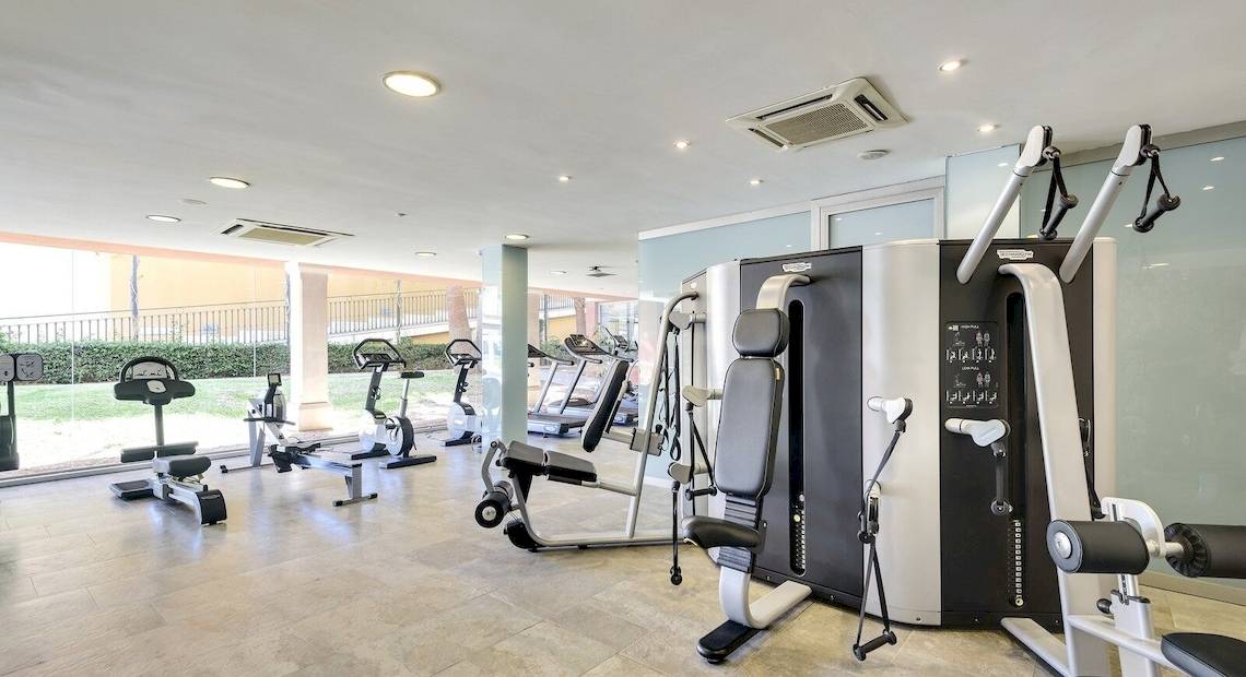 Fitnessstudio im Occidental Playa de Palma Hotel mit verschiedenen Trainingsgeräten und Blick auf den Garten.