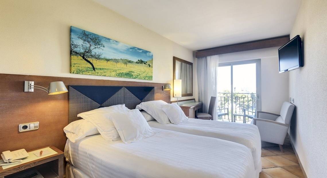 Doppelzimmer im Occidental Playa de Palma mit zwei Betten, einem Fernseher, einem Schreibtisch und einem Balkon.