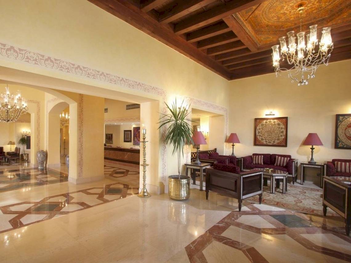 Lobby des Steigenberger Coraya Beach Hotels mit gemusterten Böden, Möbeln und Kronleuchtern.