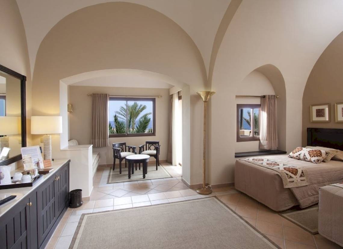 Innenansicht eines eleganten Zimmers im Steigenberger Coraya Beach Hotel mit Bett, Schreibtisch und Ausblick.