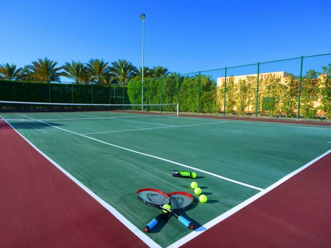 Tennisplatz im Steigenberger Coraya Beach Hotel mit zwei Tennisschlägern und Tennisbällen.