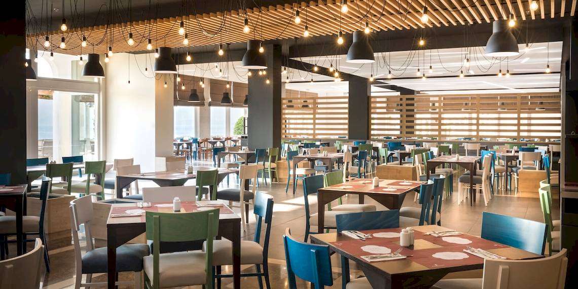Innenansicht des Restaurants im Remisens Hotel Epidaurus mit vielen bunten Tischen und Stühlen.