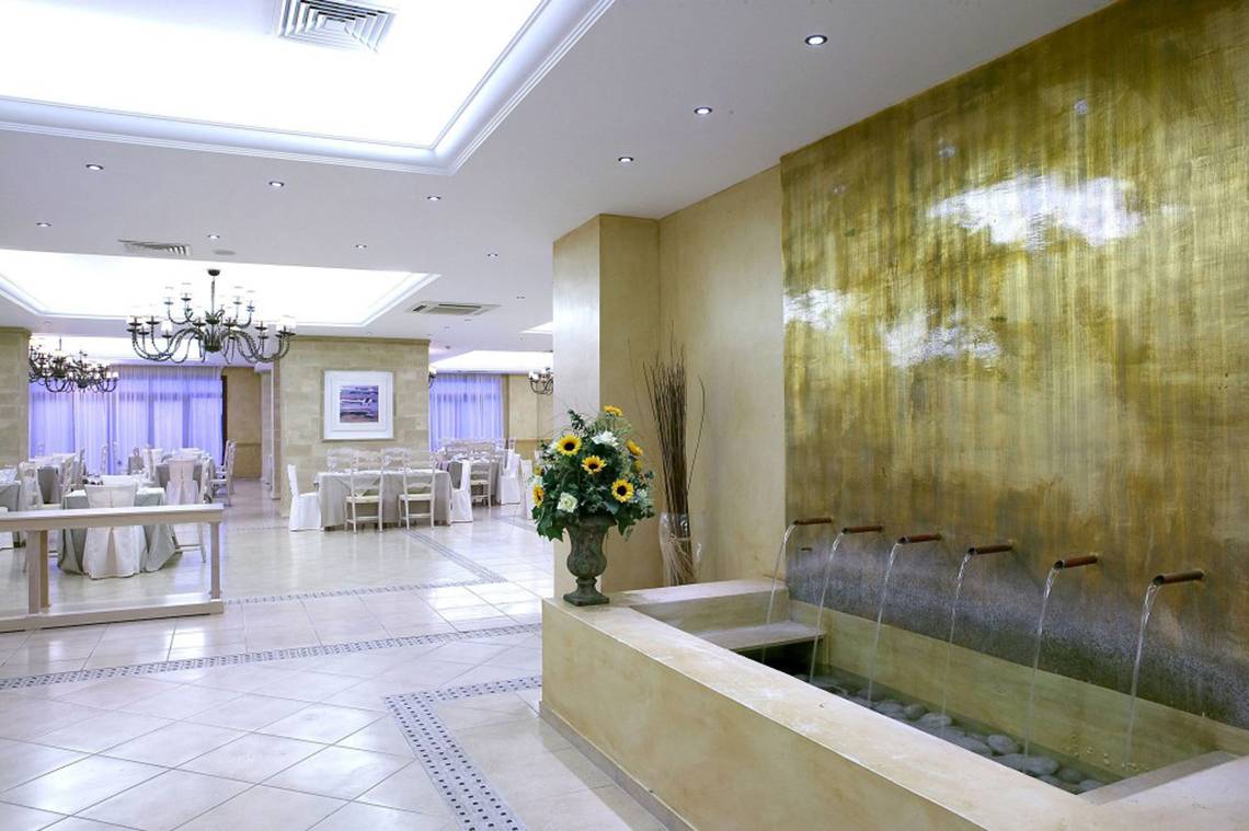 Innenbereich des Lindian Village Beach Resort Rhodes mit goldener Wand und Wasserbrunnen.