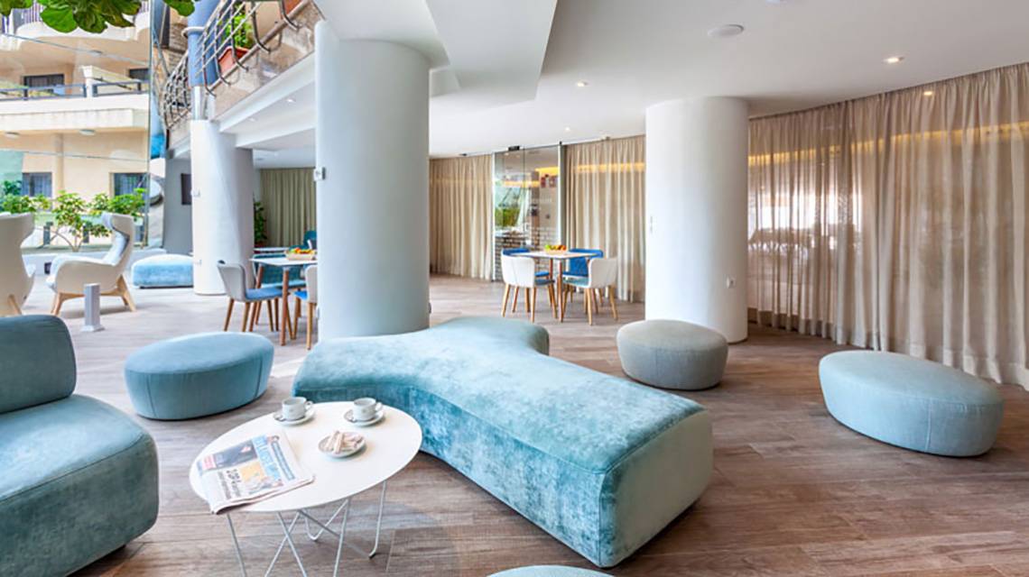 Lounge-Bereich des Tigotan Lovers & Friends Hotels mit blauen Möbeln, einem Tisch und einer Zeitschrift.