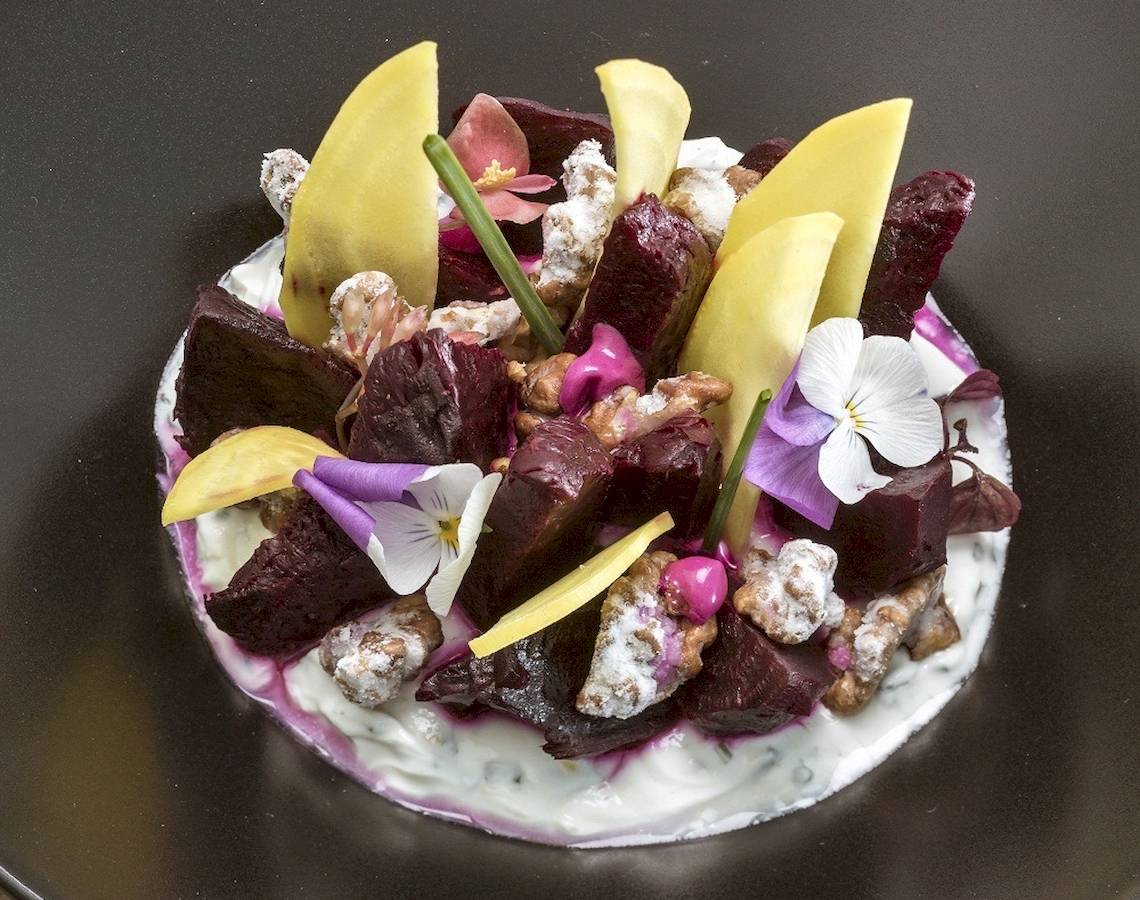 Beetroot-Platte mit verschiedenen Toppings auf einem schwarzen Teller.
