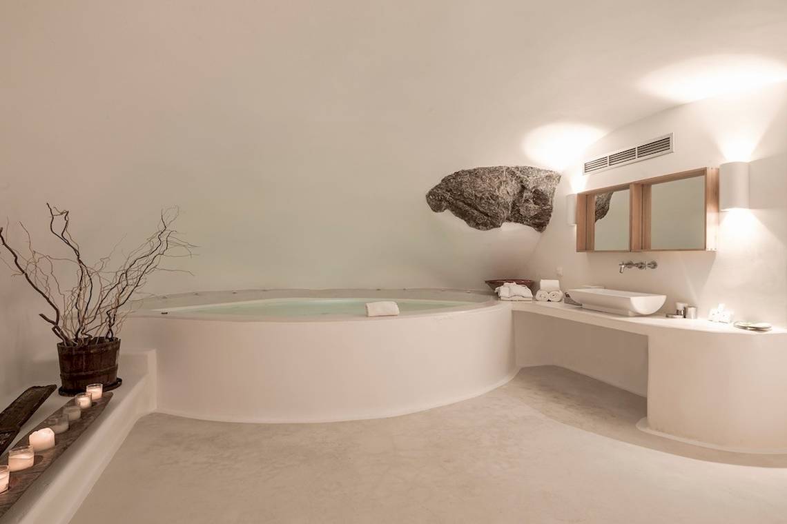 Weißes Badezimmer im Katikies Chromata Santorini Hotel mit einem großen Whirlpool und einem Waschbecken.