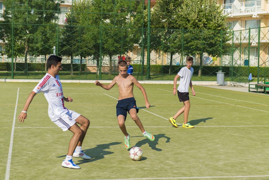 Junge spielen Fußball auf dem Sportplatz des DIT Evrika Beach Clubs.