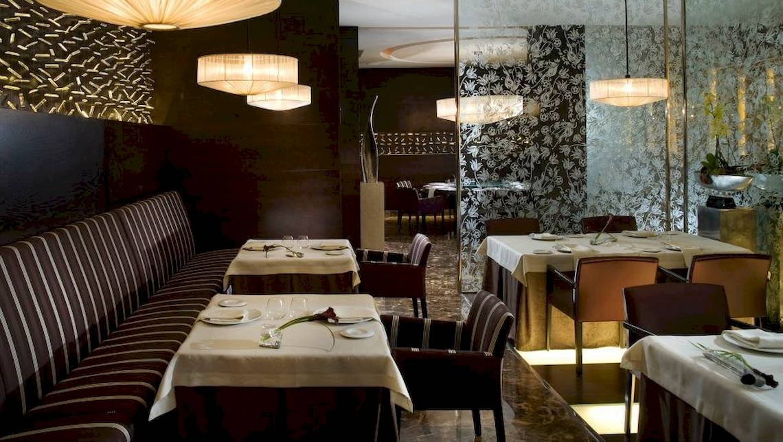 Das elegante Restaurant des Gran Melia Palacio de Isora mit gedeckten Tischen, Stühlen und Kronleuchtern.