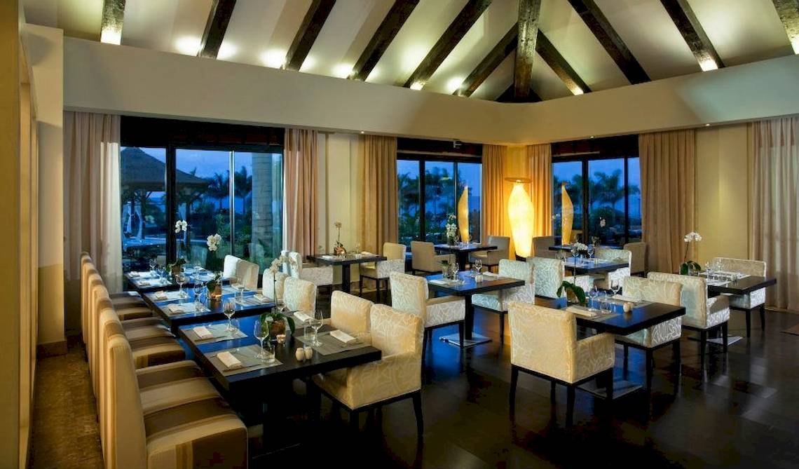 Restaurantbereich des Gran Melia Palacio de Isora mit gedeckten Tischen und Stühlen.