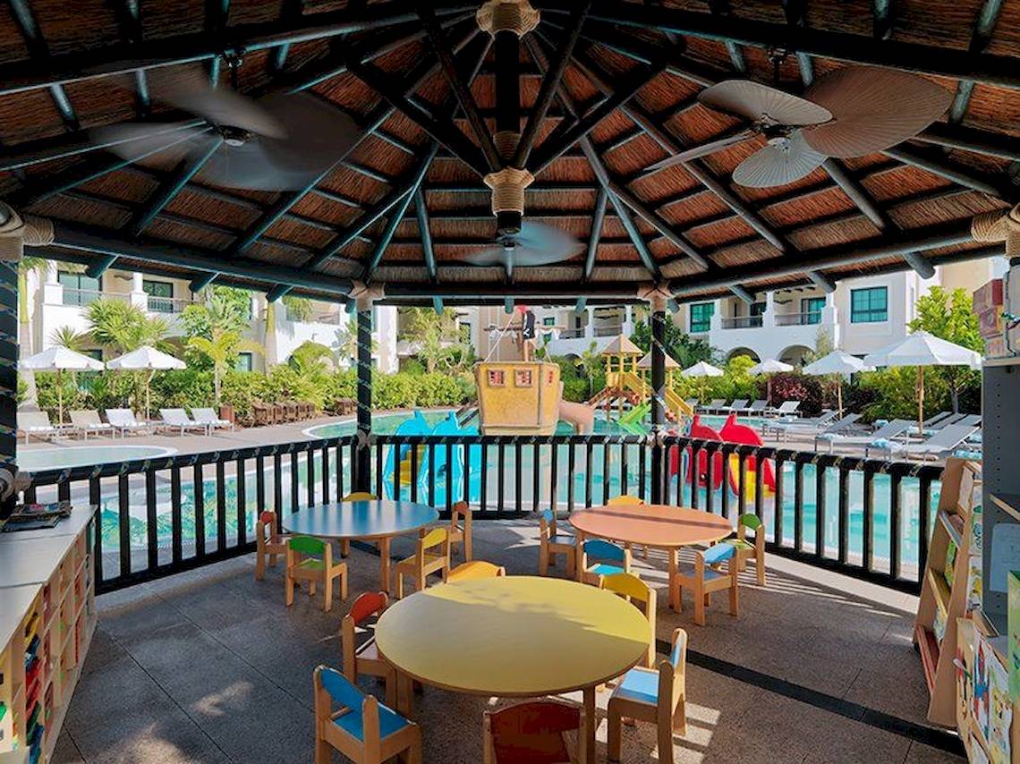 Kinder Spielbereich im Gran Melia Palacio de Isora Hotel mit bunten Tischen und Spielgeräten.