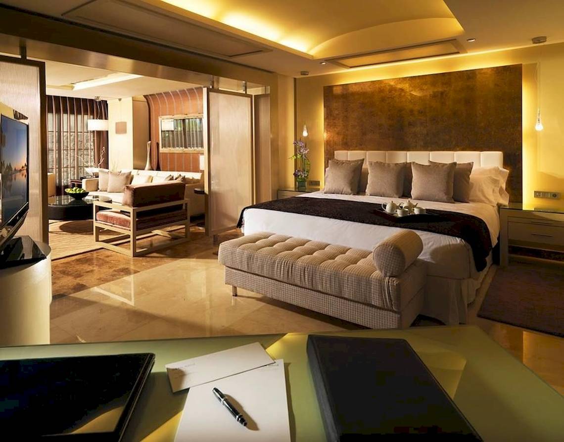 Gran Melia Palacio de Isora Suite Zimmer mit Bett, Sofa und Schreibtisch.