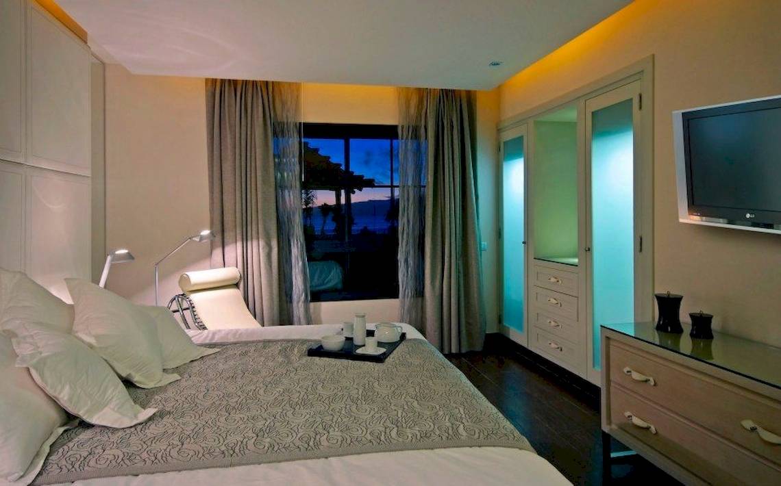 Schlafzimmer Ansicht im Gran Melia Palacio de Isora Hotel mit Bett, Nachttisch und Fernseher.