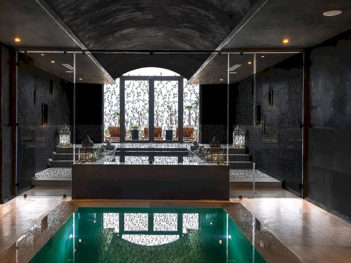 Innenpool im Hyatt Place Taghazout Bay mit schwarzer Wandverkleidung und Glaswänden.