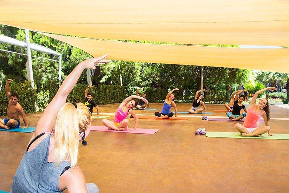 Yoga-Kurs im Freien im Blue Waters Club mit mehreren Teilnehmern und einer Instruktorin.