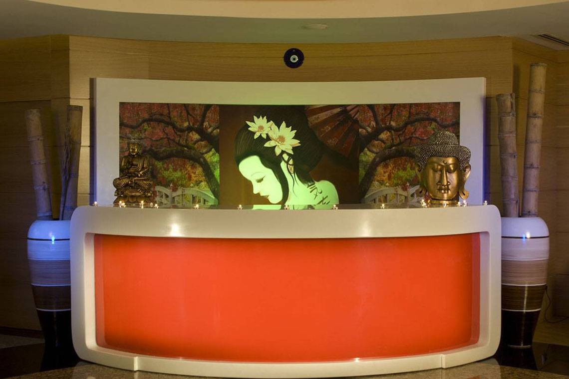 Empfangsbereich des Blue Waters Club Hotels mit rotem Empfangstresen und asiatischen Dekorationselementen.