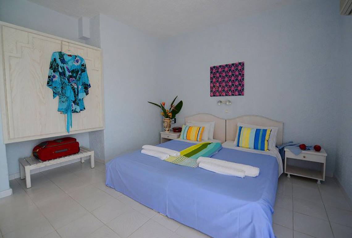 Schlafzimmer im Golden Star Hotel in Kos mit blauem Bett und weißen Möbeln.