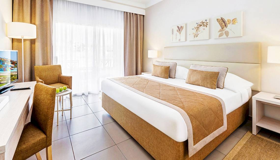Ein Hotelzimmer im Jaz Aquaviva mit einem Bett, Schreibtisch und Stühlen.