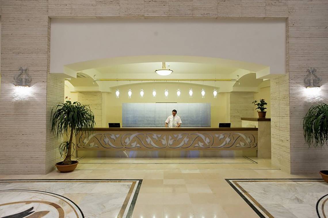 Empfangsbereich des Melas Lara Hotels mit Rezeptionist hinter dem Empfangstresen.