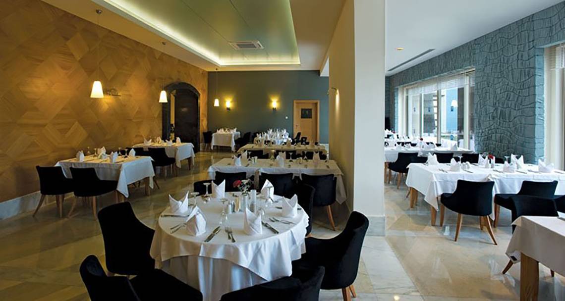 Foto von einem eleganten Restaurant im Melas Lara Hotel mit gedeckten Tischen und modernen Möbeln.