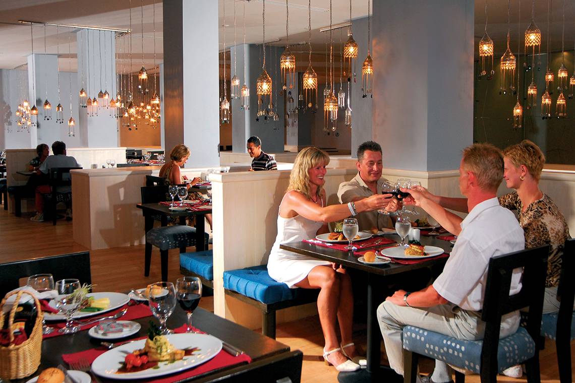 Gäste im Restaurant des Grand Hotel Sharm El Sheikh sitzen an Tischen und trinken auf das Essen an.