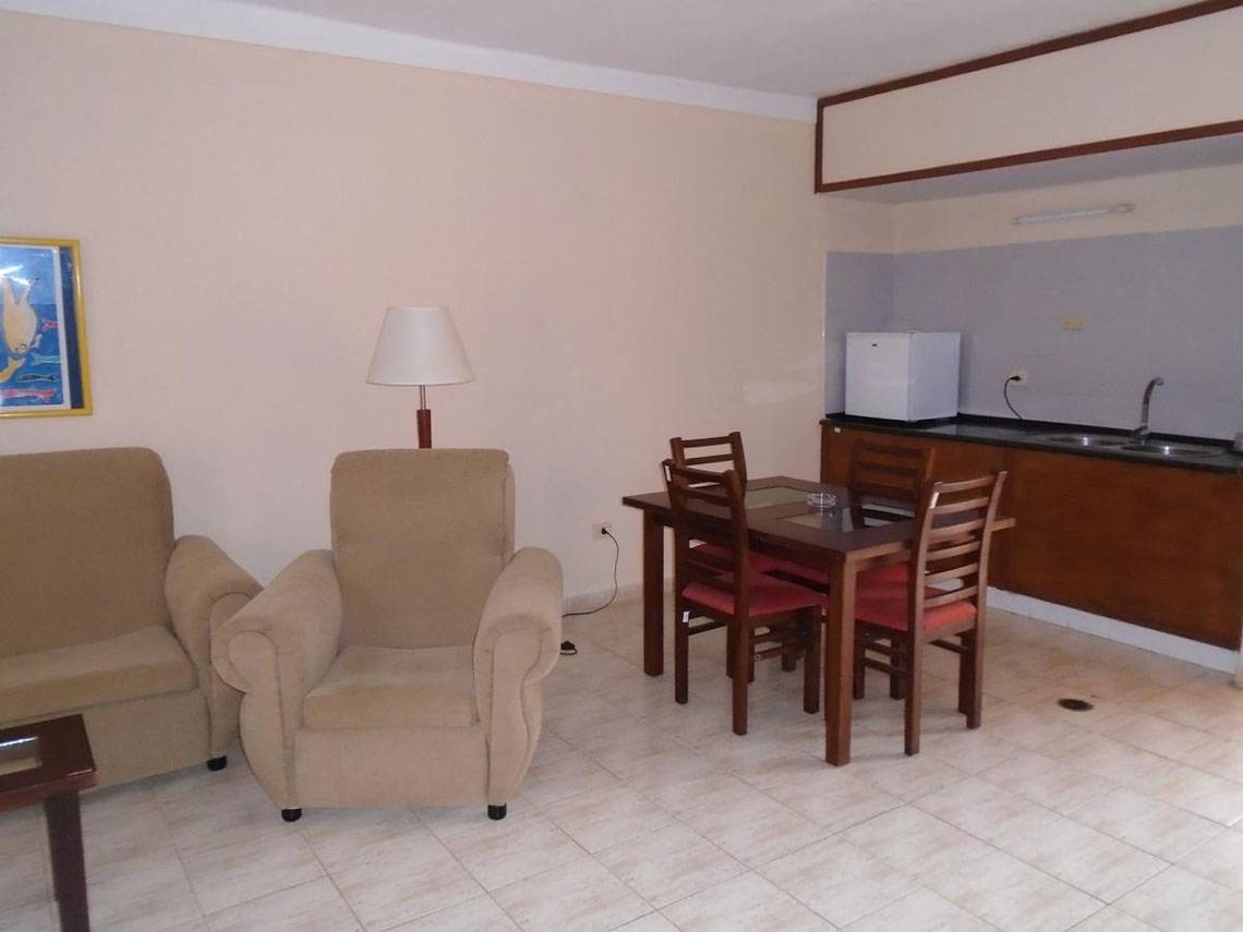 Das Wohnzimmer des ROC Arenas Doradas Hotels mit Sitzmöbeln, Tisch und Lampe.