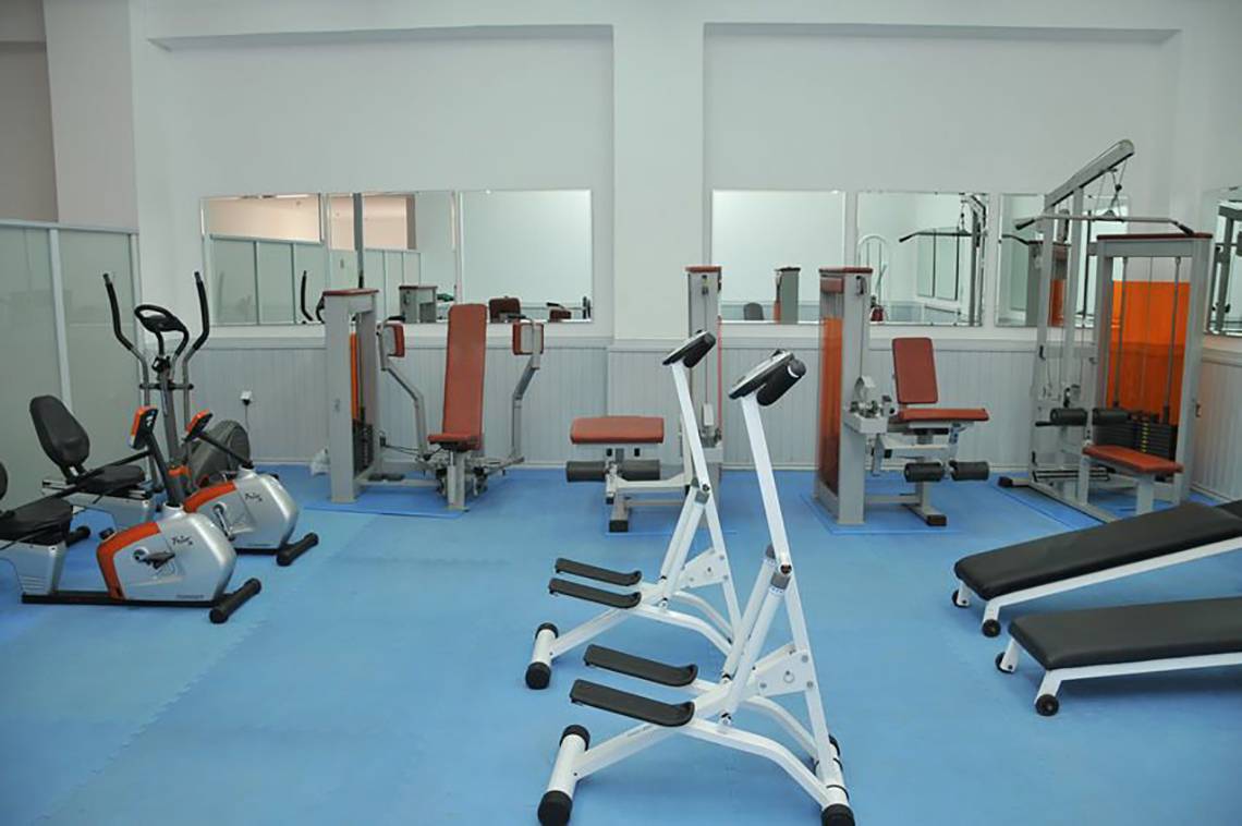 Fitnessstudio im Mastichari Bay Hotel mit verschiedenen Geräten auf blauem Boden.