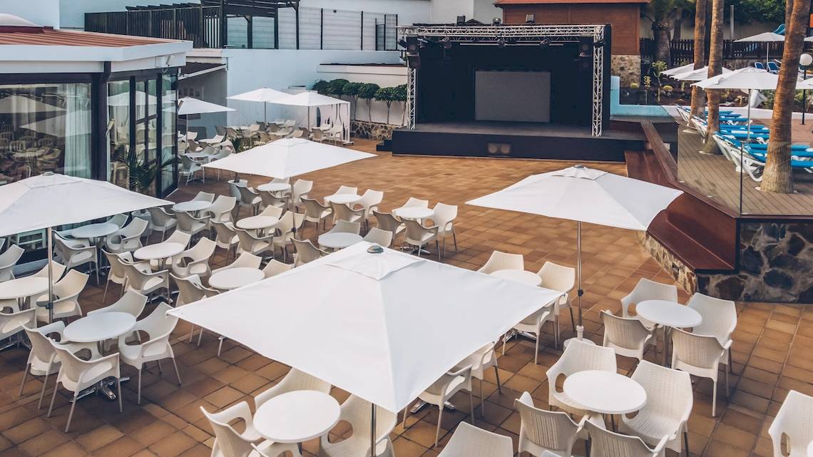 Oberirdische Terrasse des Iberostar Las Dalias Hotels mit Tischen, Stühlen und Sonnenschirmen.