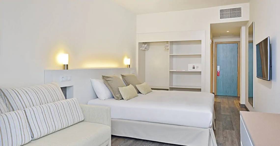 Innenansicht eines Hotelzimmers im Sol Barbados mit einem Bett, Sofa, Lampen und Fernseher.