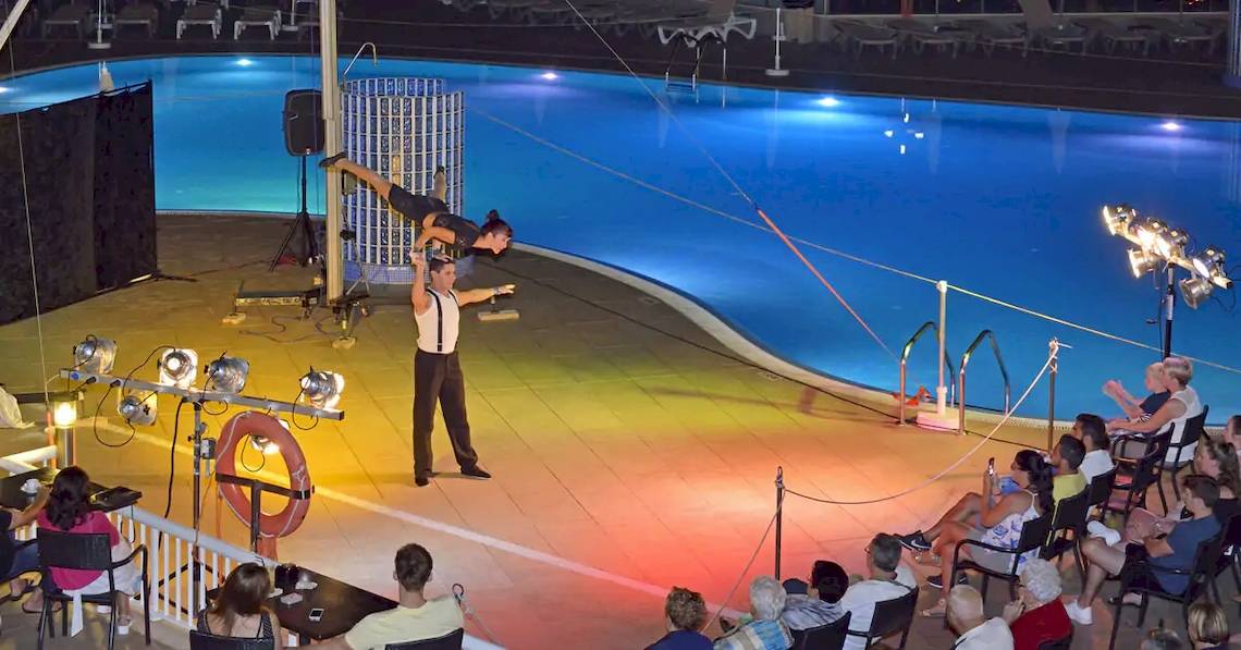 Akrobaten führen eine Show über einem Swimmingpool im Sol Barbados Hotel auf.