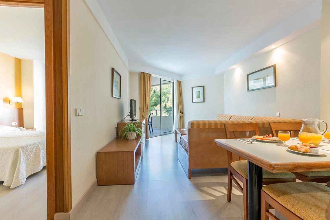 Innenansicht einer Suite im Hipotels Bahia Grande, mit Schlafzimmer, Wohnzimmer und Balkon.