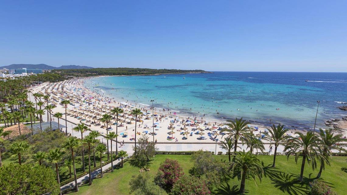 Luftaufnahme des Hipotels Bahia Grande Strandes mit vielen Gästen, Palmen und türkisfarbenem Meer