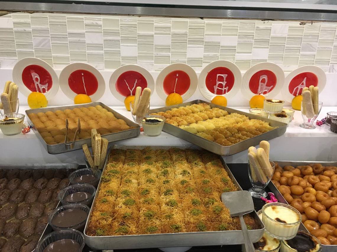 Süßigkeiten-Buffet im Riviera Hotel & Spa mit verschiedenen Desserts, darunter orientalische Gebäcke, Schokoladenkuchen und Donuts.