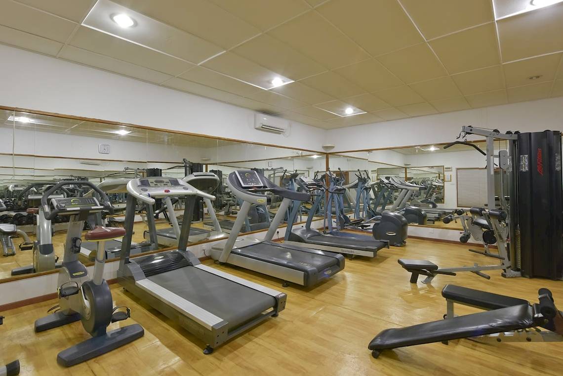 Fitnesscenter im Thulhagiri Island Resort mit Laufbändern, Kraftgeräten und Spiegeln.