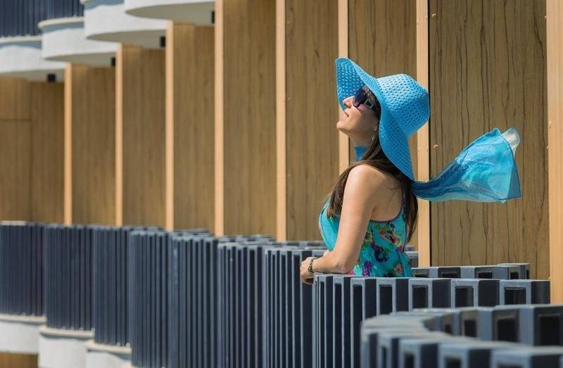 Eine Frau im HVD Club Bor Hotel steht vor einer blauen Wand und schaut in den Himmel.