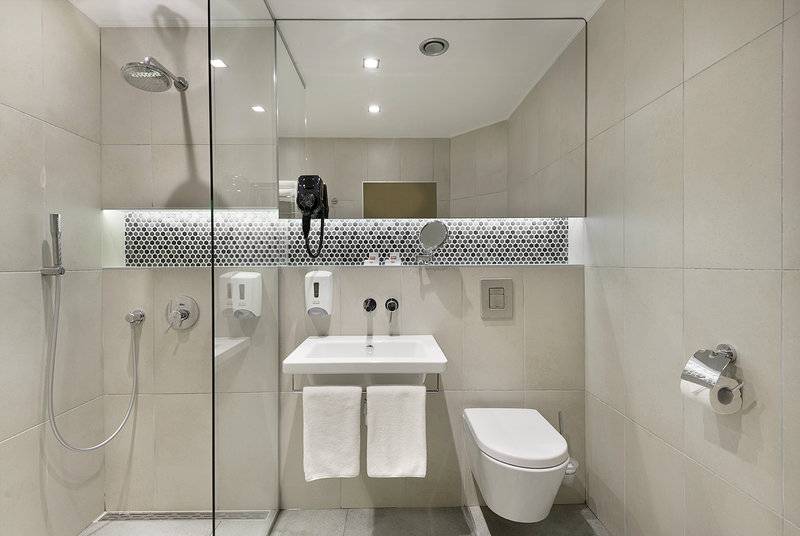 Badezimmer des HVD Club Bor Hotels mit Glasdusche, Toilette und Waschbecken.
