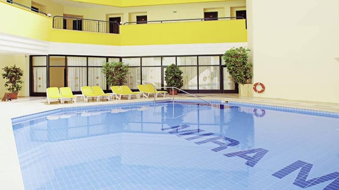 Poolbereich im Miramare Beach Hotel mit gelben Sonnenliegen und blauem Wasser.