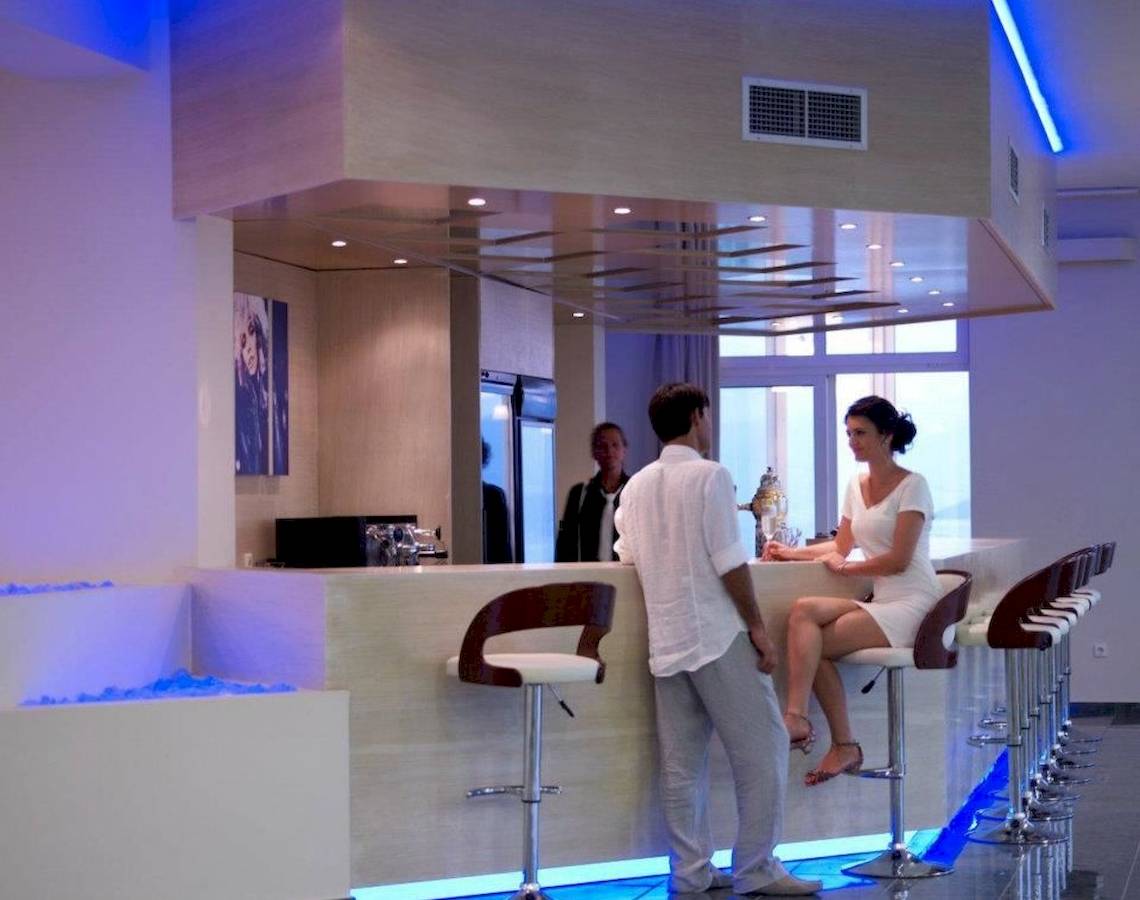 Ein Paar steht an der Bar im Proteas Blu Resort, während zwei Personen im Hintergrund stehen.