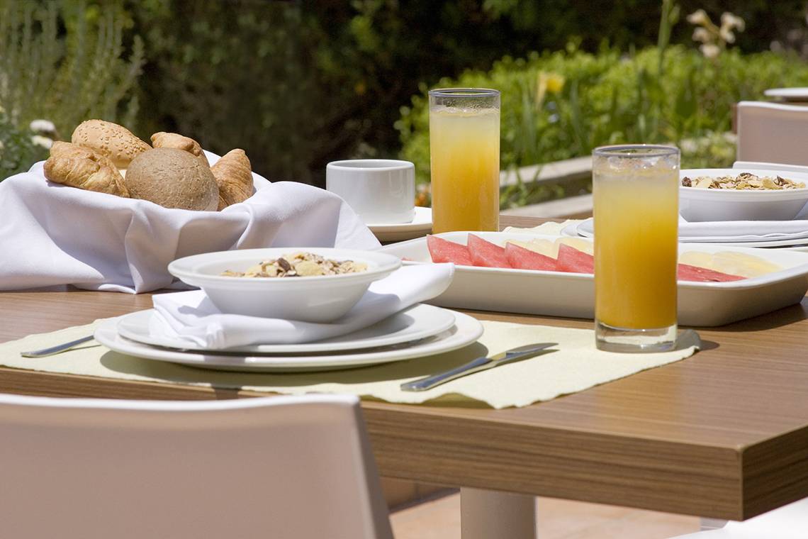Frühstückstisch im Venus Beach Hotel mit Brot, Orangensaft und Müsli.