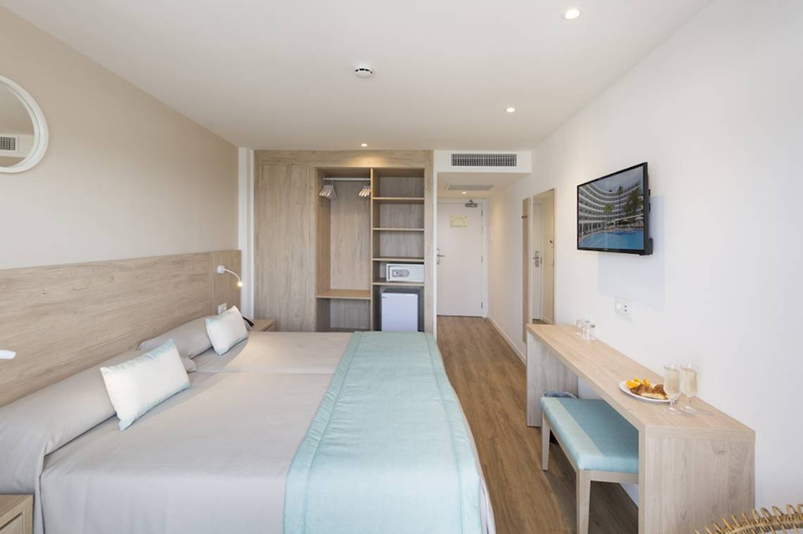 Innenansicht eines Zimmers im HSM Linda Playa Hotel mit zwei Betten, einem Schreibtisch und einem Fernseher.