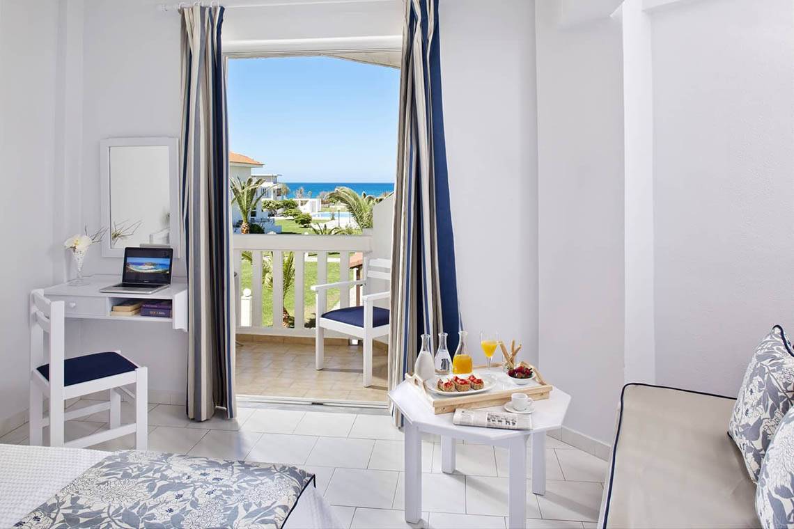 Innenansicht eines Zimmers im Mrs Chryssana Beach Hotel mit Blick auf den Balkon und das Meer.