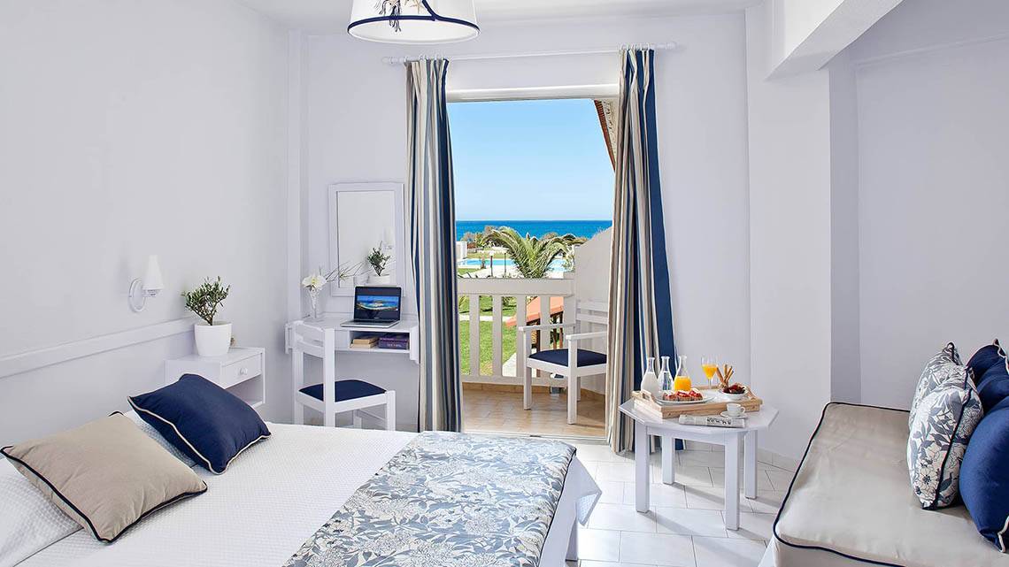 Zimmer im Mrs Chryssana Beach Hotel mit Balkon, Schreibtisch und Meerblick.